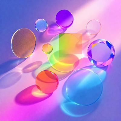 The primary subject of the image is a collection of colorful glass balls, which are placed on a blue surface. The setting appears to be a studio or workspace, as the glass balls are arranged in a visually appealing manner. The visual style of the image is a combination of photo and digital art, creating a vibrant and lively atmosphere. The dominant colors in the image are blue, orange, and purple, which contribute to the overall mood of the scene.